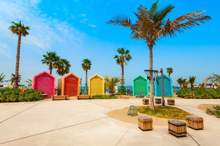 Colorful beach huts line the sandy shores inviting relaxation and fun. Enjoy sun-soaked days filled with beach activities amidst swaying palm trees and stunning coastal views at La Mer Dubai.